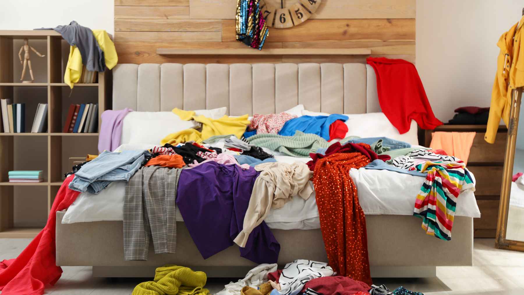 A cluttered bedroom with unmade sheets and clothes scattered across the floor.