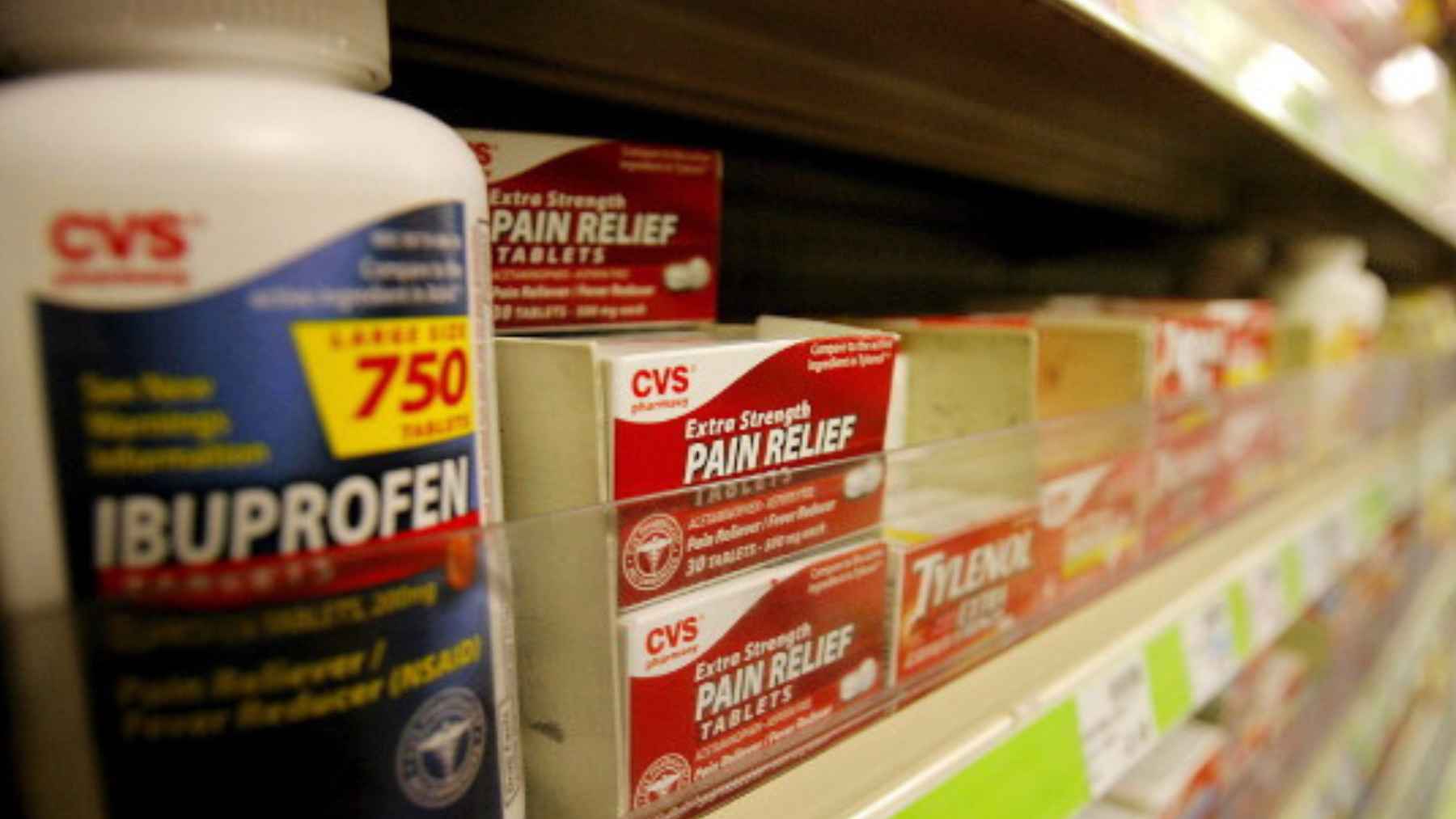 Over-the-counter painkillers displayed on a pharmacy shelf, including ibuprofen and other common pain relief medicines.