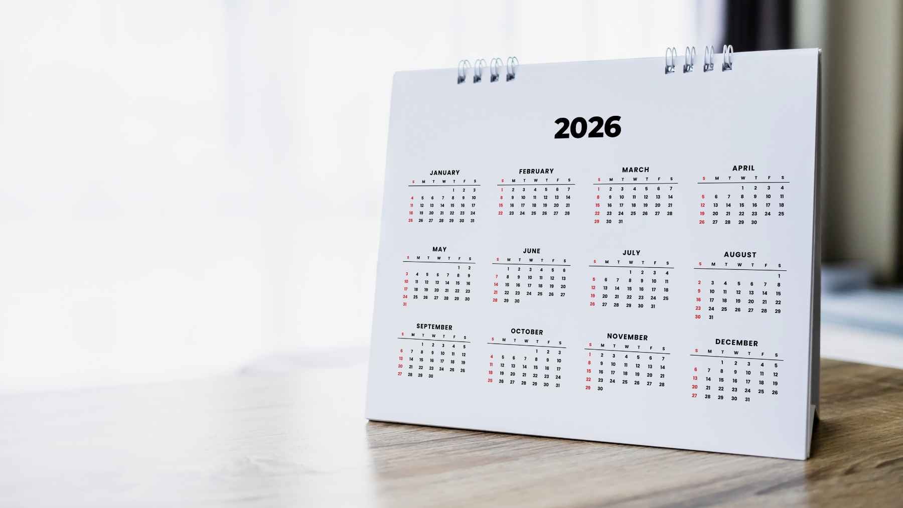 A person writing handwritten daily plans and notes inside an open paper planner calendar.
