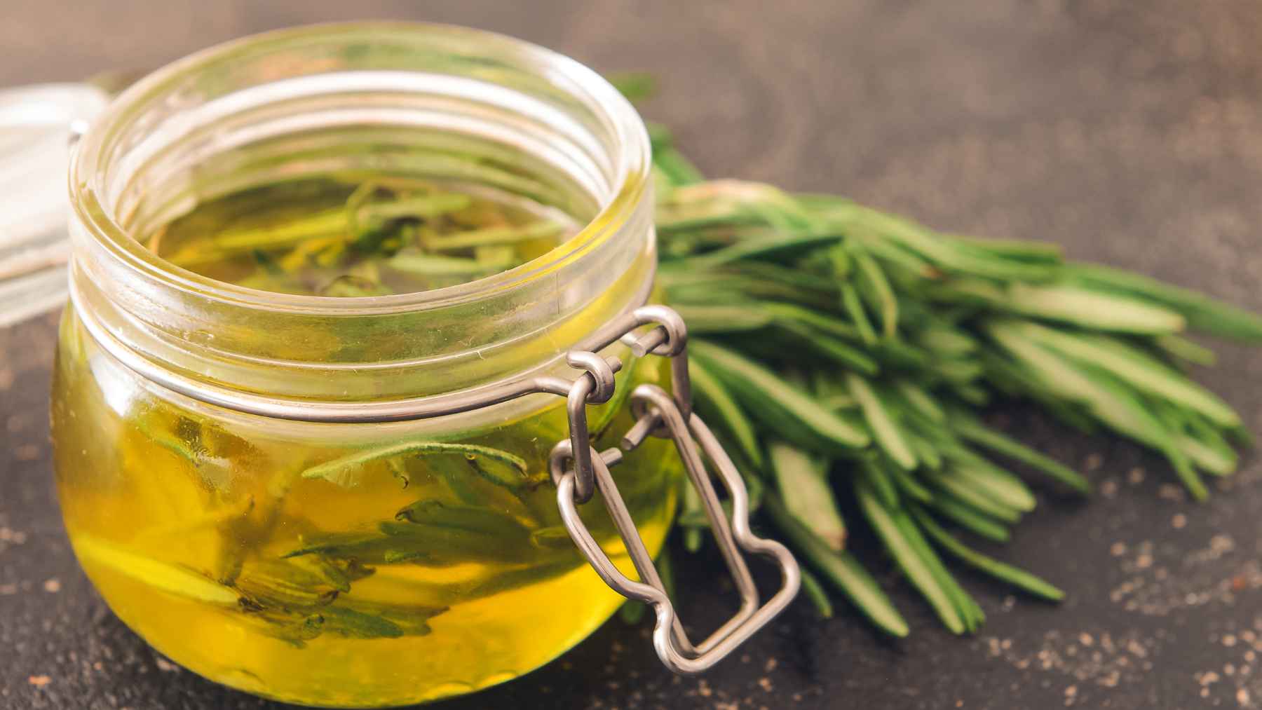 Fresh rosemary sprigs arranged in a glass jar in a bedroom, illustrating the popular home habit of using rosemary for scent and relaxation