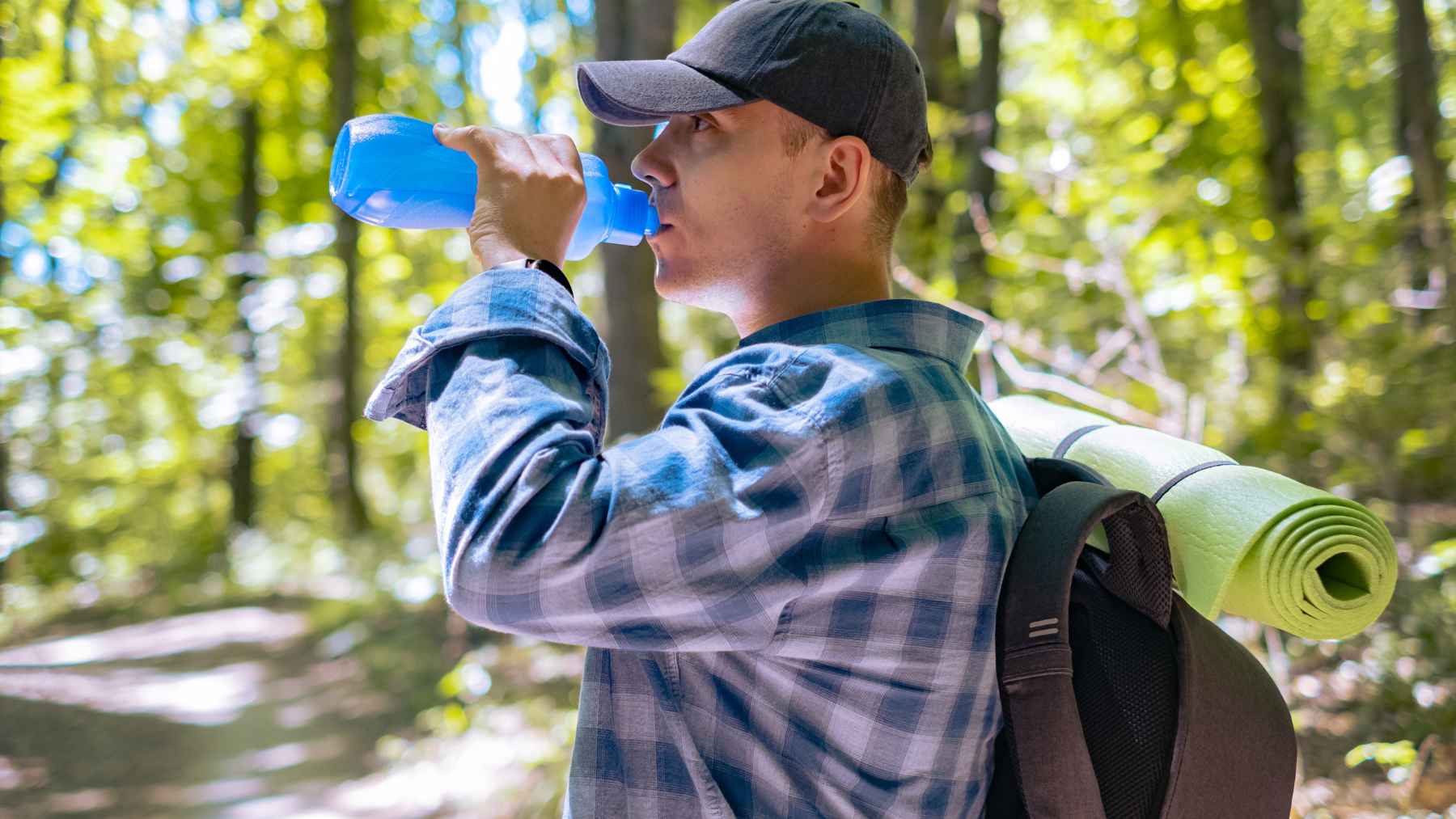 A person hiking outdoors on a nature trail while wearing a weighted backpack for a rucking workout.