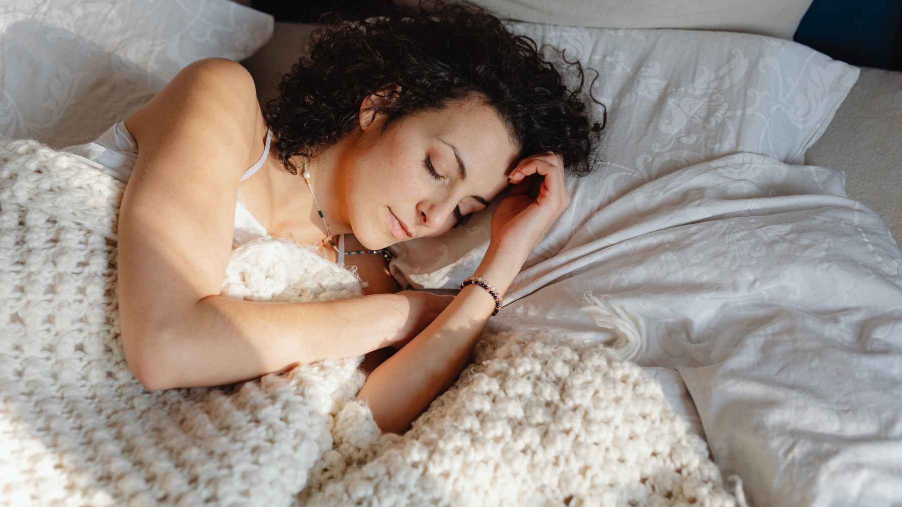 Person sleeping on their left side, a position associated with improved digestion and reduced nighttime acid reflux.
