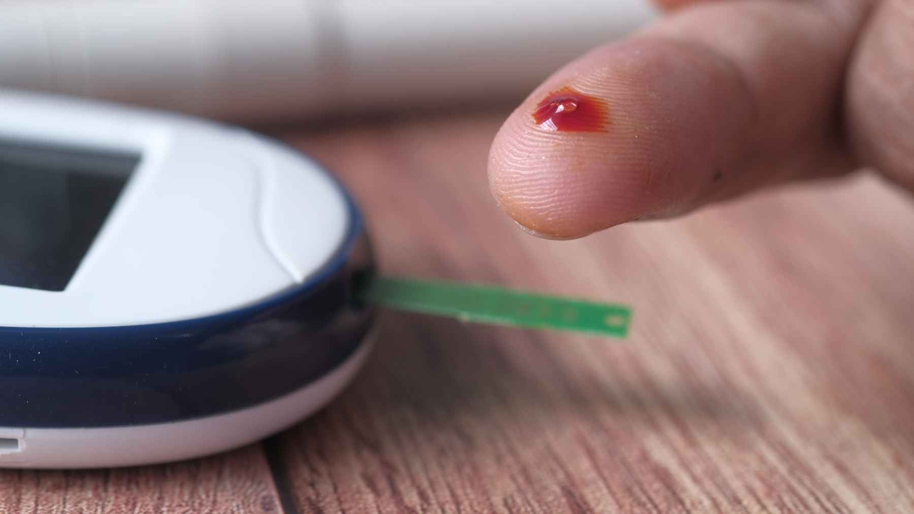 Blood glucose being measured with a glucose meter and finger prick.