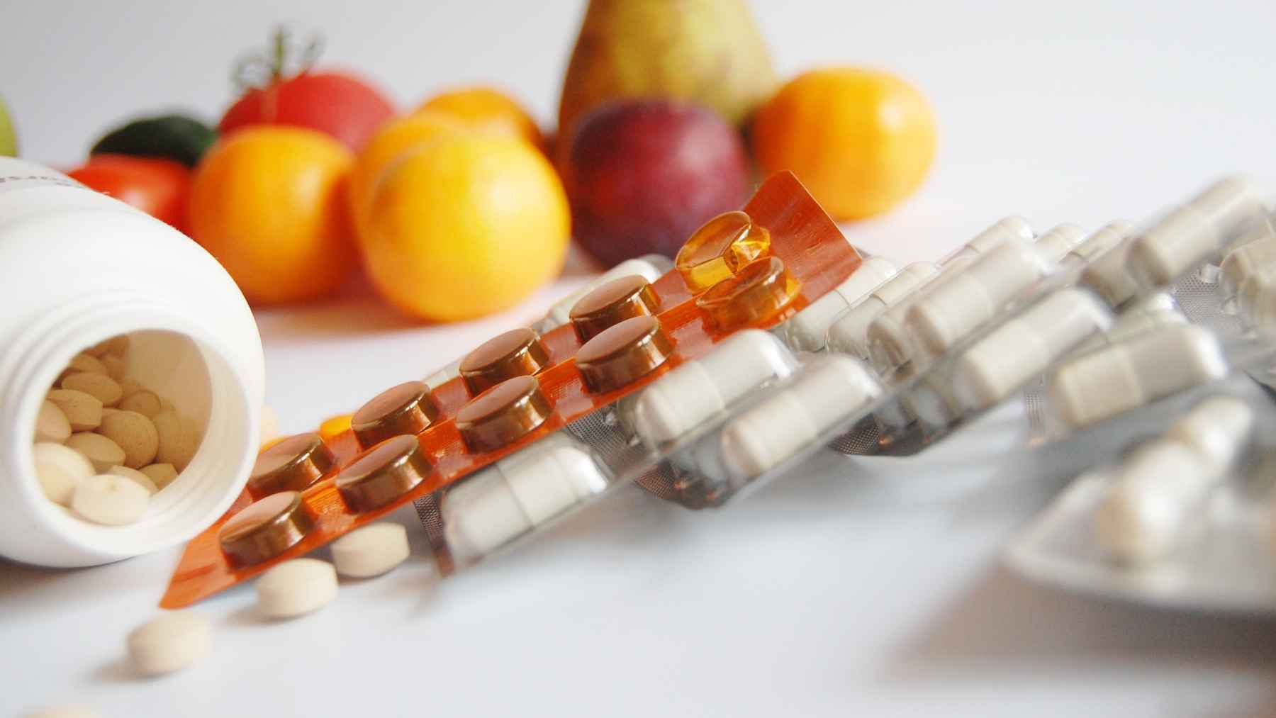 Vitamin D supplements and tablets alongside fresh fruit, illustrating winter vitamin D intake and nutrition