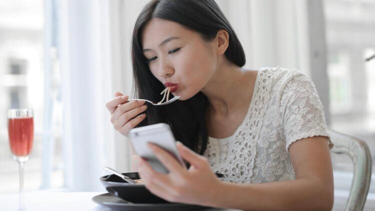 Mujer comiendo, móvil