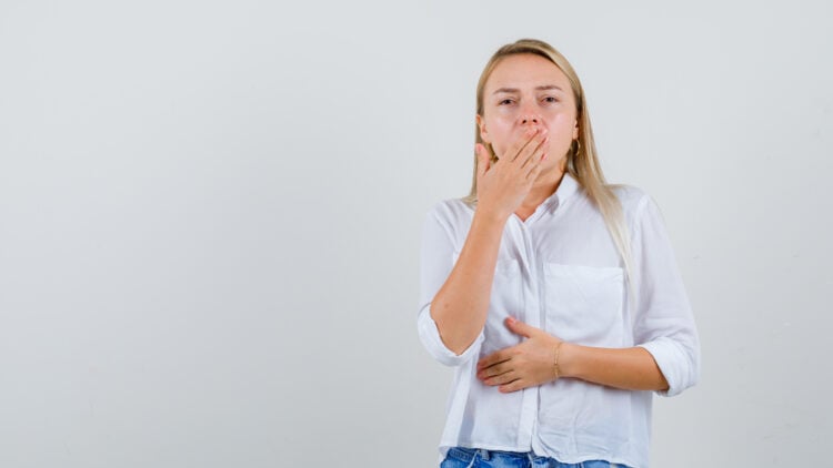 Mujer, boca tapada, eructo, mano en la panza