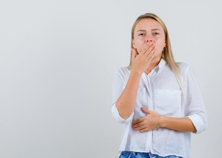 Mujer, boca tapada, eructo, mano en la panza