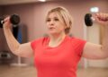 Una mujer entrenando la fuerza con mancuernas. (Foto: Freepik)