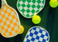 Palas de pickleball de colores vivos y pelotas dispuestas en una soleada pista deportiva. Foto: Lindsey Flynn - Pexels