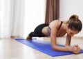Una joven mujer realizando ejercicio de plancha abdominal. Foto: Freepik - @cookie_studio