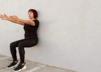 Una mujer adulta haciendo el ejercicio de sentadilla de pared. Foto: Freepik