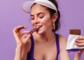 Una mujer con vestimenta deportiva come chocolate. Foto: @lookstudio - Freepik