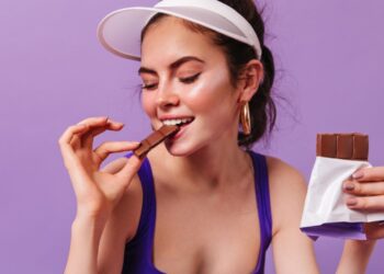 Una mujer con vestimenta deportiva come chocolate. Foto: @lookstudio - Freepik