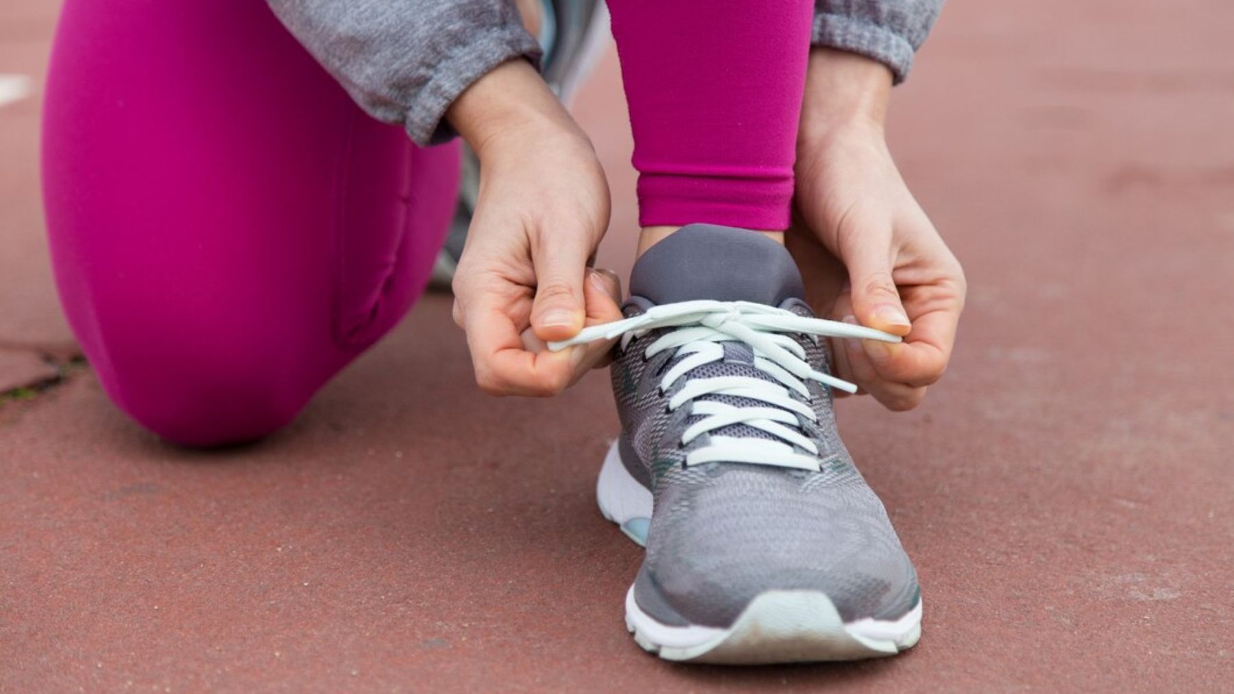 Primer plano de un mujer atándose el cordón de las zapatillas deportivas. Foto: katemangostar / Freepik.