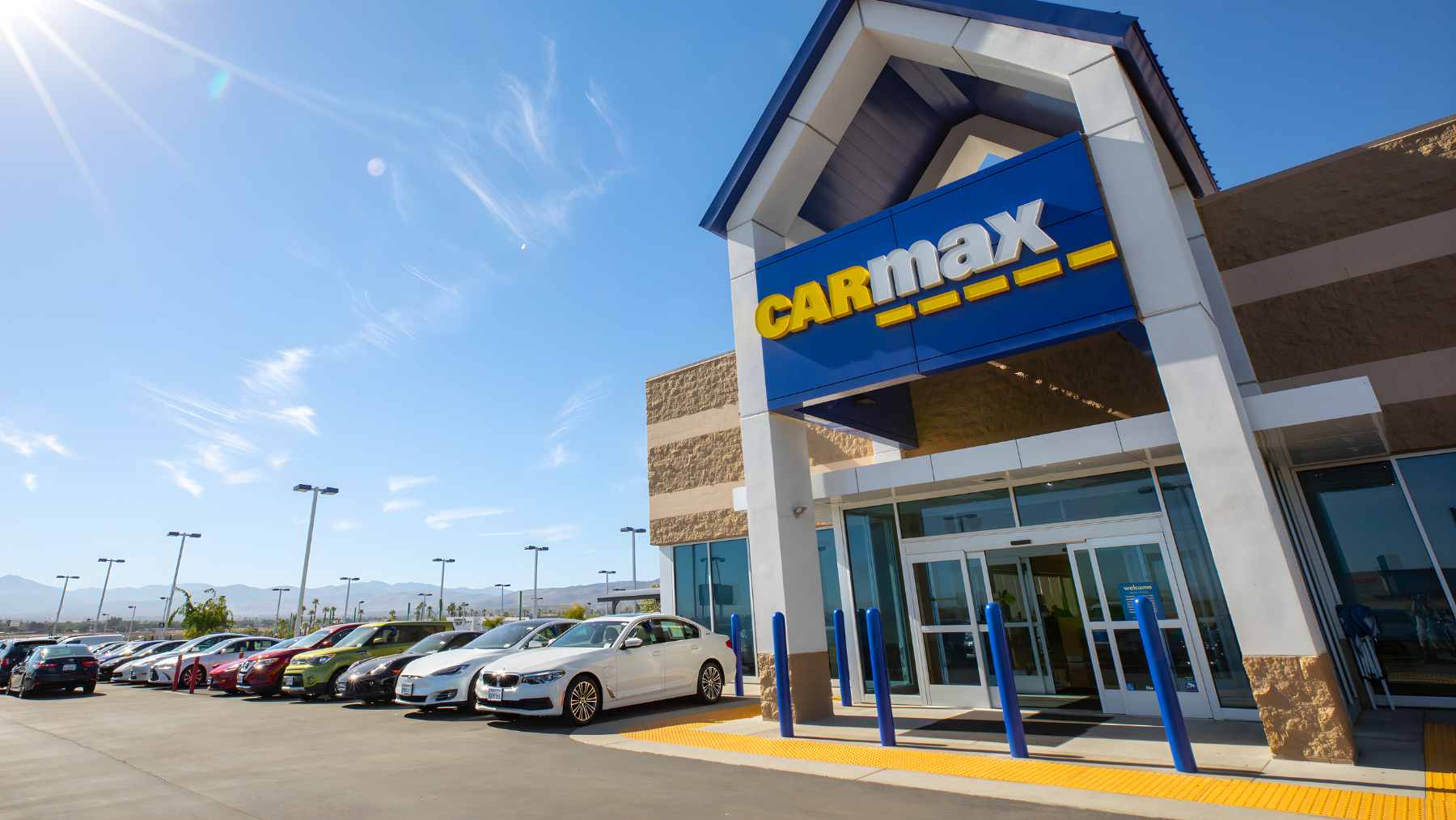 A row of used vehicles parked at a CarMax dealership lot.