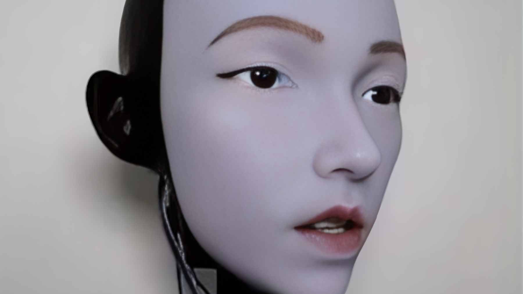 The EMO humanoid robot face, featuring 26 actuators beneath a silicone skin, practicing lip-syncing gestures in front of a mirror.