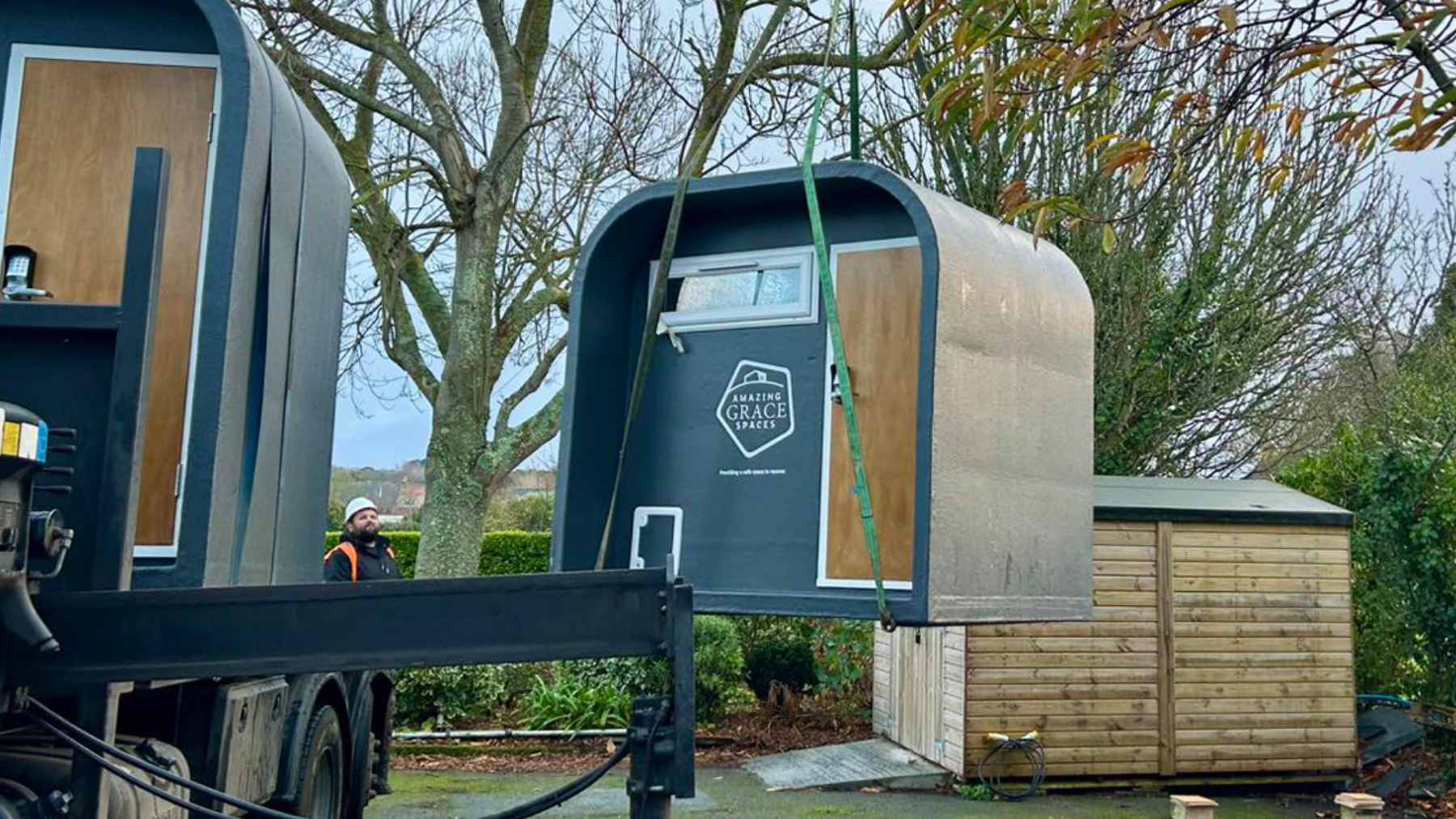 A compact, white solar-powered emergency sleeping pod situated in a Guernsey car park to provide short-term shelter for the homeless.