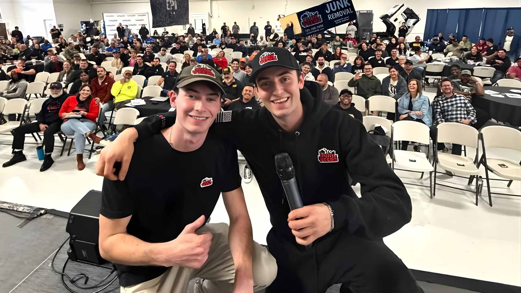 Kirk and Jacob McKinney, the Gen Z founders of Junk Teens, standing in front of their professional junk removal truck in Massachusetts.