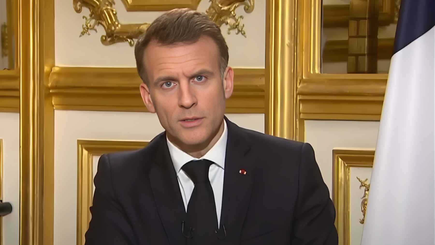 President Emmanuel Macron delivering a speech at the Île Longue nuclear submarine base, flanked by naval personnel and strategic military assets.