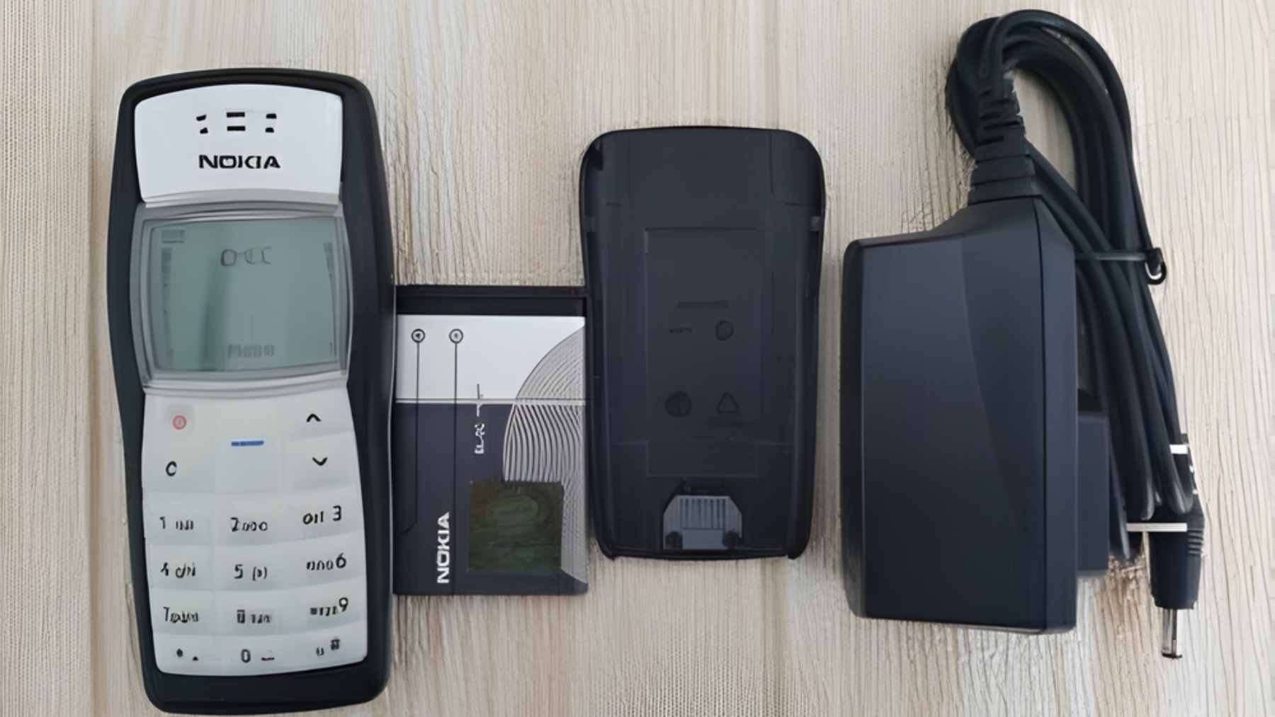 A classic silver Nokia 1100 mobile phone with its iconic monochrome screen and rubberized keypad.