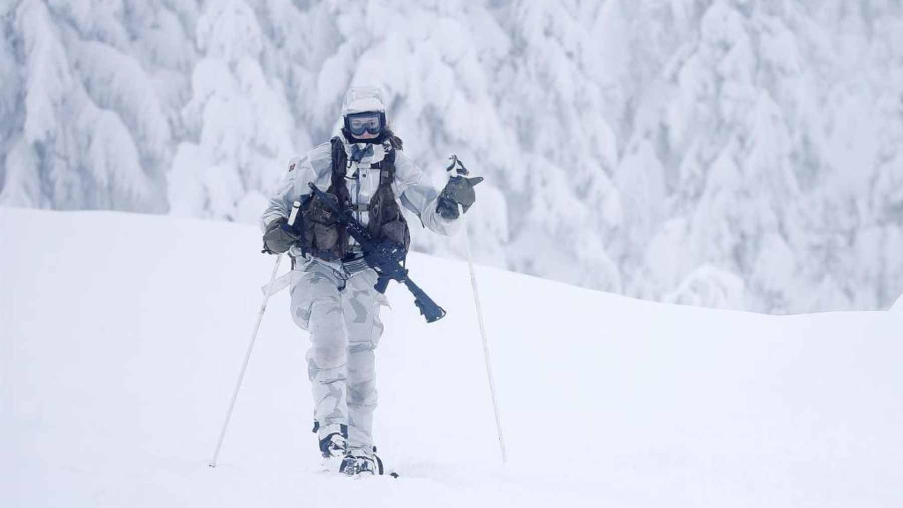 Norwegian elite reconnaissance soldiers digging a quinzhee snow cave for thermal concealment during a military exercise.