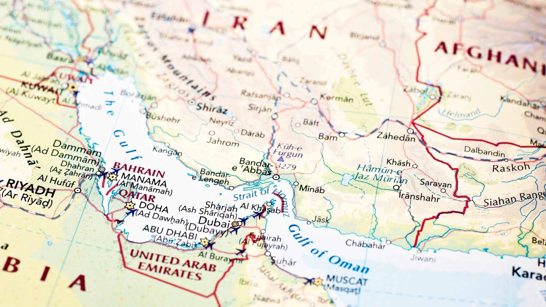 A commercial oil tanker navigating the narrow shipping lanes of the Strait of Hormuz under maritime surveillance.