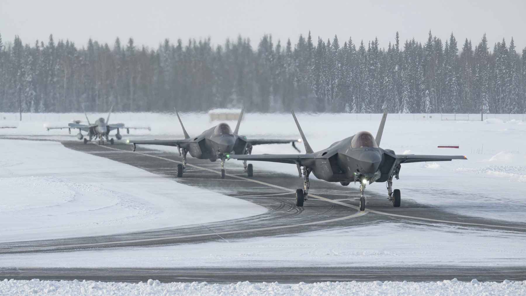 Two U.S. Air Force F-35A Lightning II fighter jets and two F-22 Raptors flying in formation alongside a Russian Tu-142 maritime reconnaissance aircraft over the Arctic.
