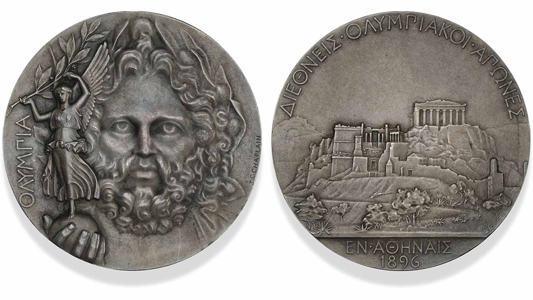A close-up view of the 1896 Athens Olympic silver medal featuring the engraved image of Zeus and Nike.
