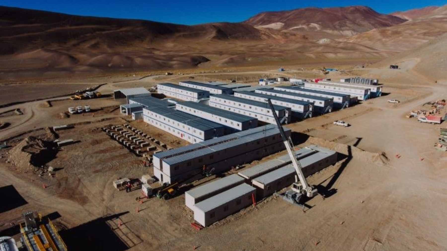 An expansive, dusty open-pit copper mining operation nestled high within the snow-capped peaks of the Andes mountains.