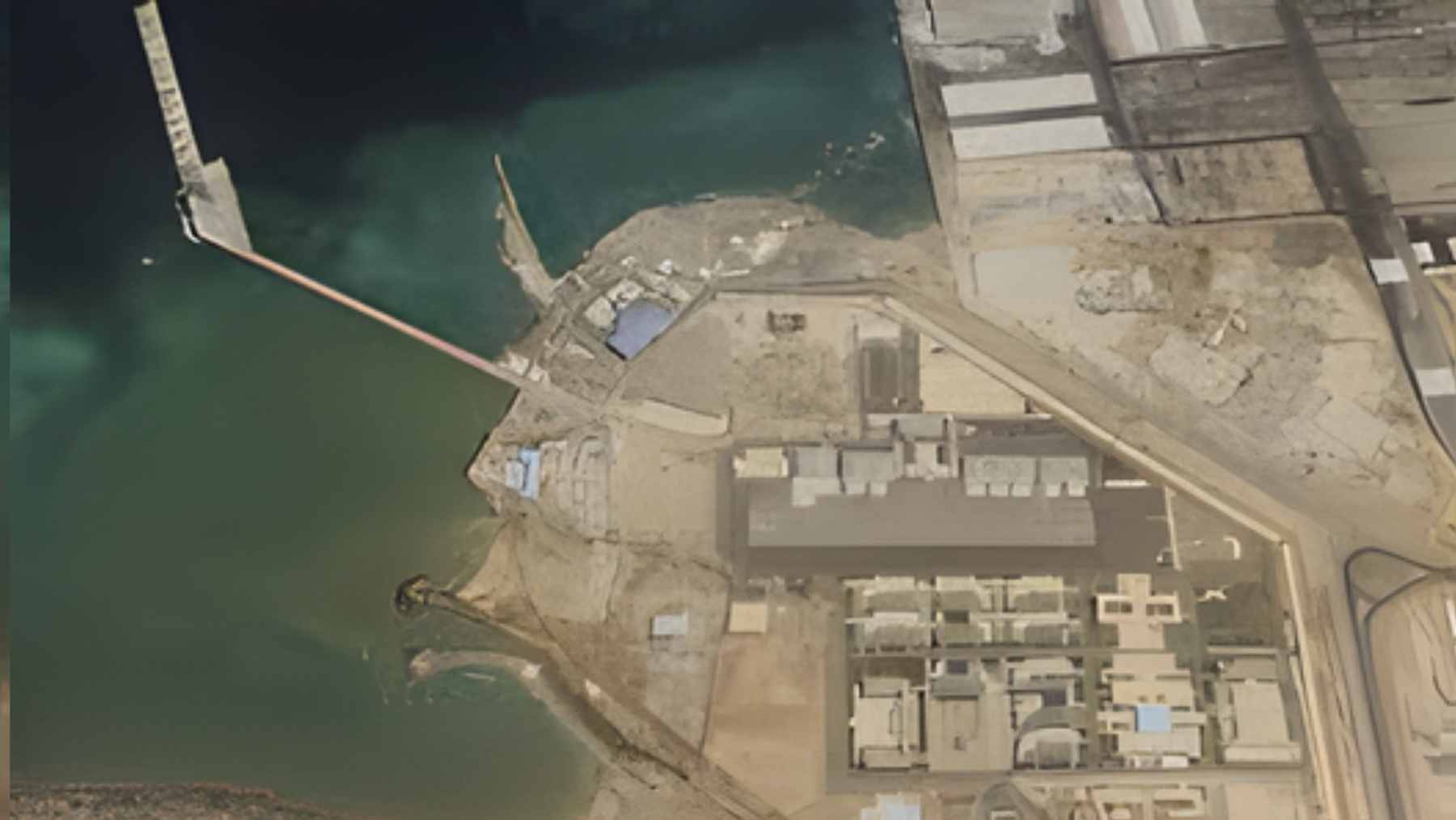 An aerial view of a massive naval and military base facility located on the arid coastline of Djibouti near the Red Sea.