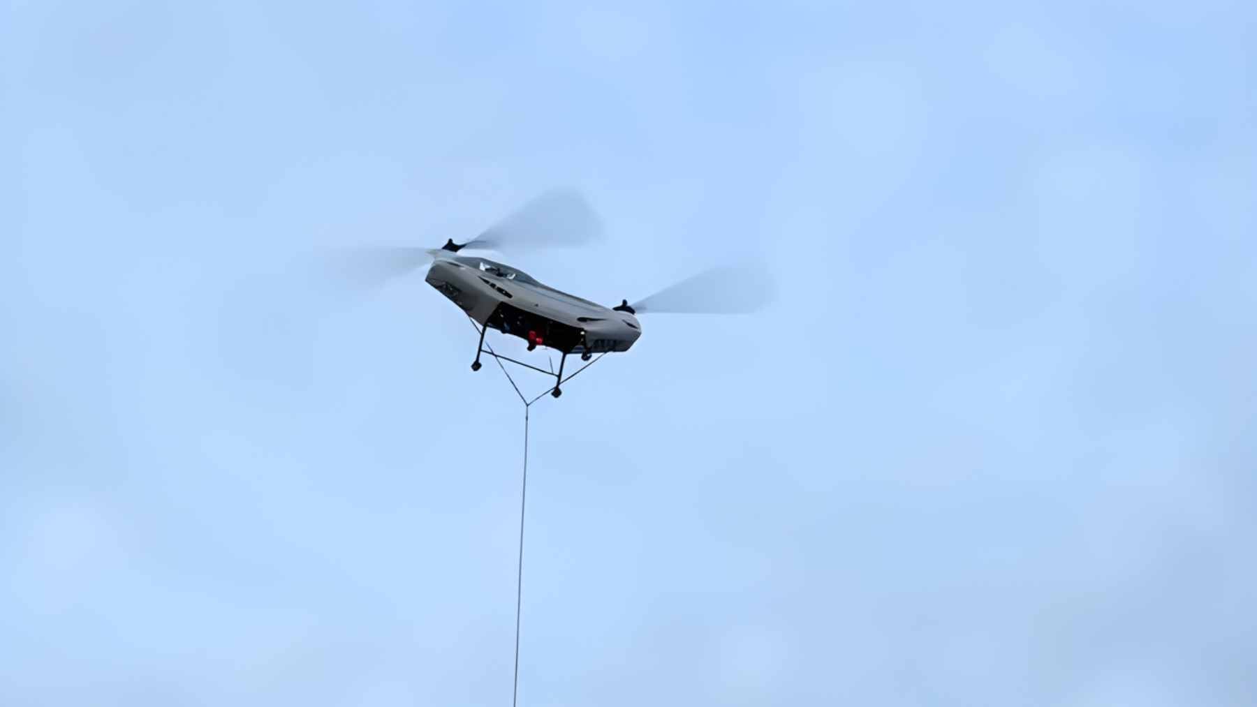 A heavy-lift Chinese unmanned cargo helicopter carrying a large payload over rugged mountainous terrain.