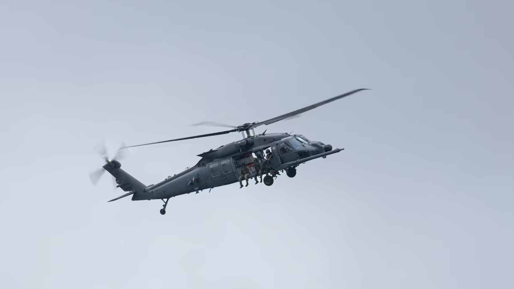 A U.S. military rescue helicopter performing maneuvers in a rugged, hostile environment during a combat search and rescue operation.