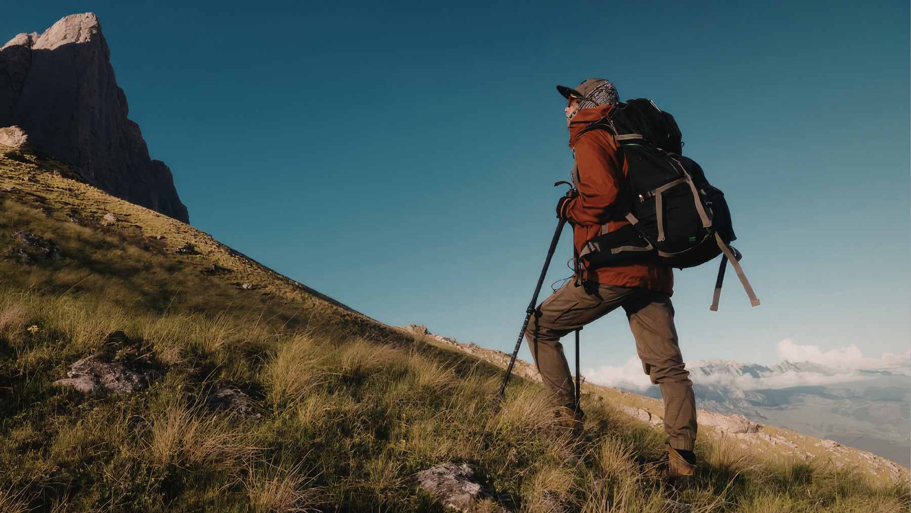 An unprepared day hiker checking a smartphone with zero signal on a rocky, high-altitude mountain trail.