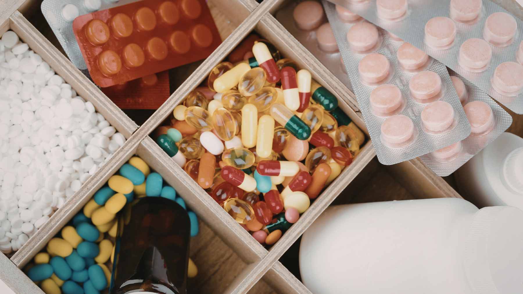 A close-up view of a pharmacist's hand counting prescription pills on a tray next to an open pill bottle.
