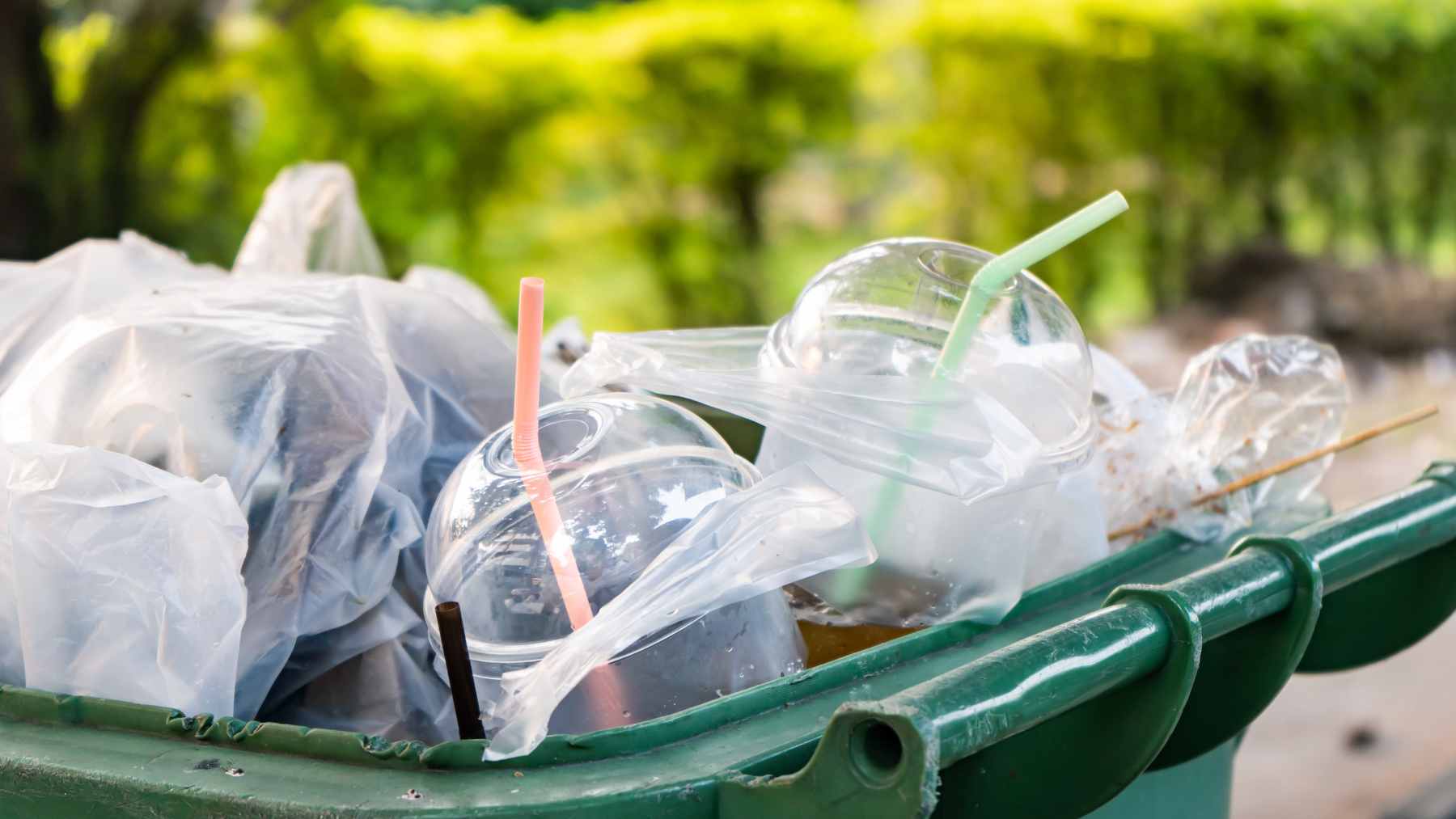 A shopper placing groceries into a reusable cloth bag at a supermarket checkout lane.