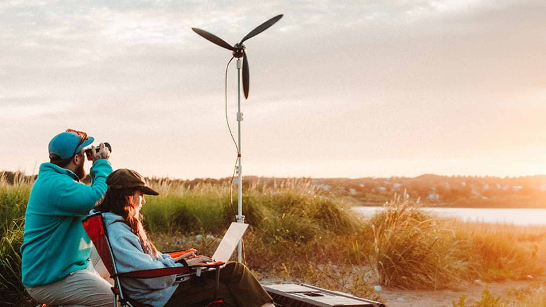 A compact, portable Shine 2.0 wind turbine set up on a tripod in a grassy outdoor landscape.