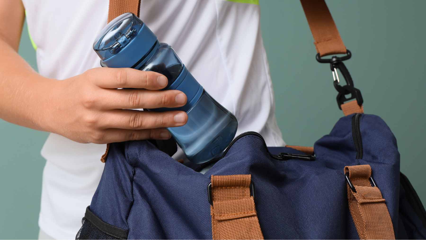 A close-up view of a disassembled reusable water bottle and its lid components soaking in soapy water next to a cleaning brush.
