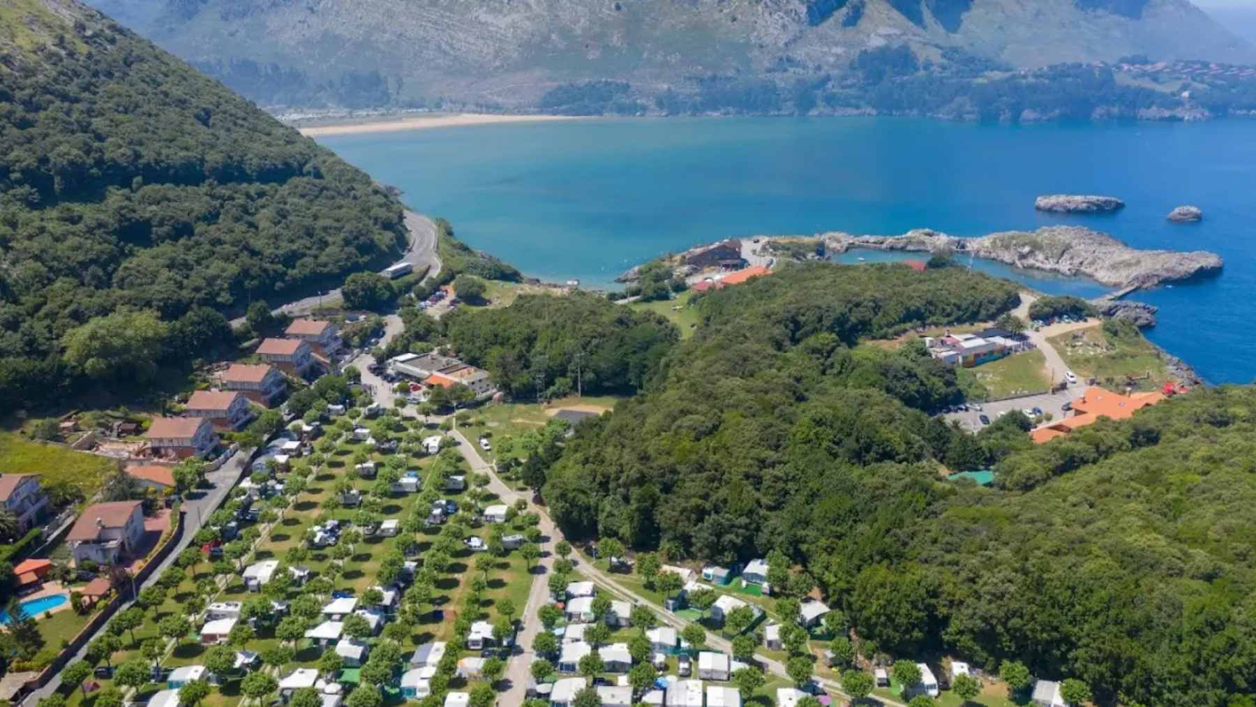 A scenic, quiet Spanish mountain village featuring traditional stone houses surrounded by dense rural forests.