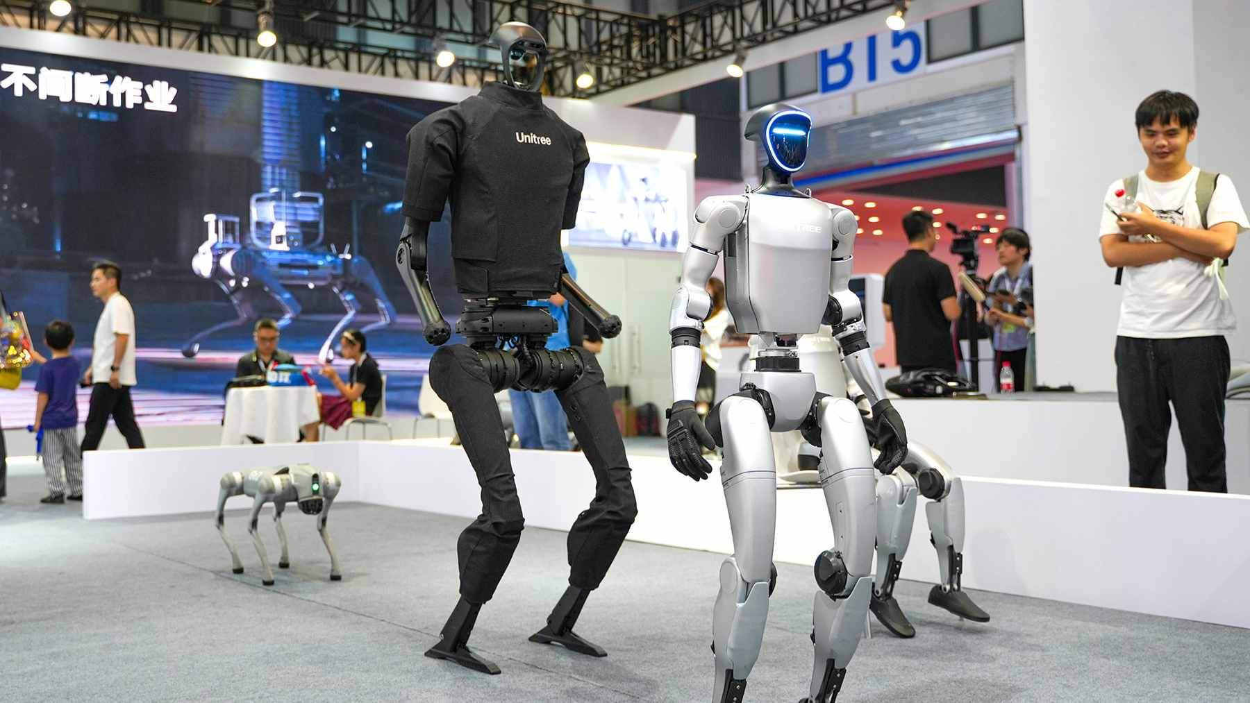 The Unitree R1 humanoid robot standing fully assembled next to its retail packaging.