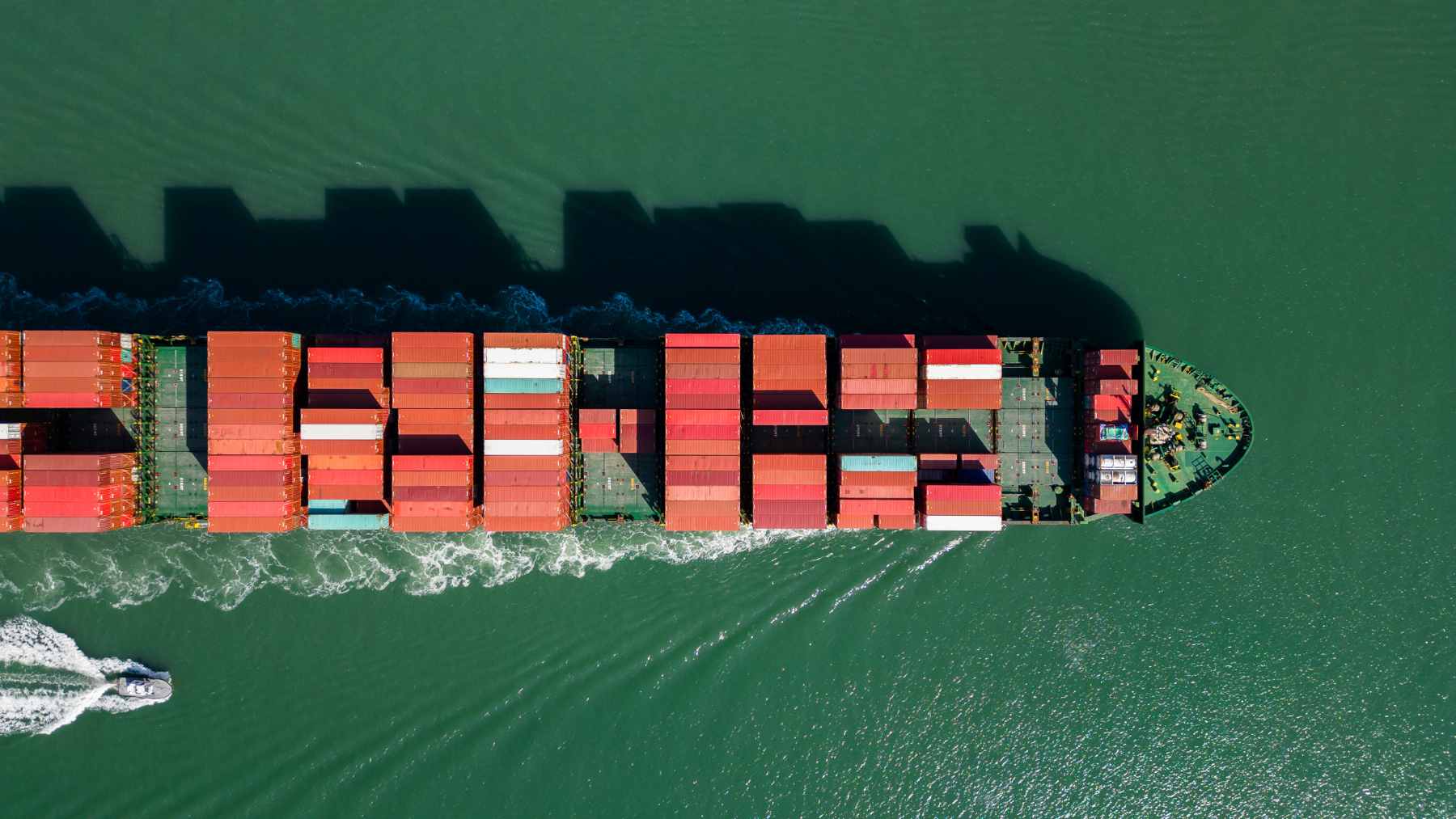 A massive commercial tanker ship sailing smoothly across the open ocean, leaving a white wake behind it.