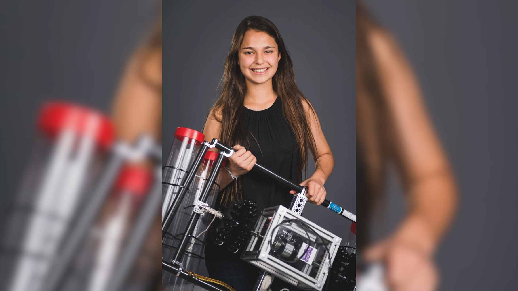 A 15-year-old girl demonstrating her $12 BEACON ocean current generator prototype, made from a PVC tube and a 3D-printed propeller.