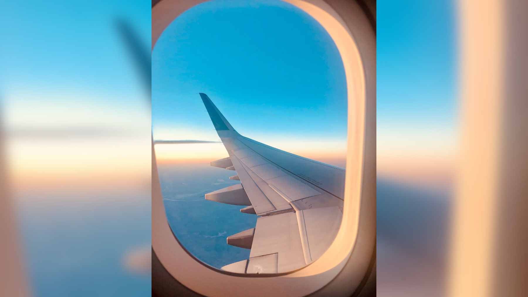 A close-up view of the small breather hole located in the middle pane of a multi-layered airplane window.