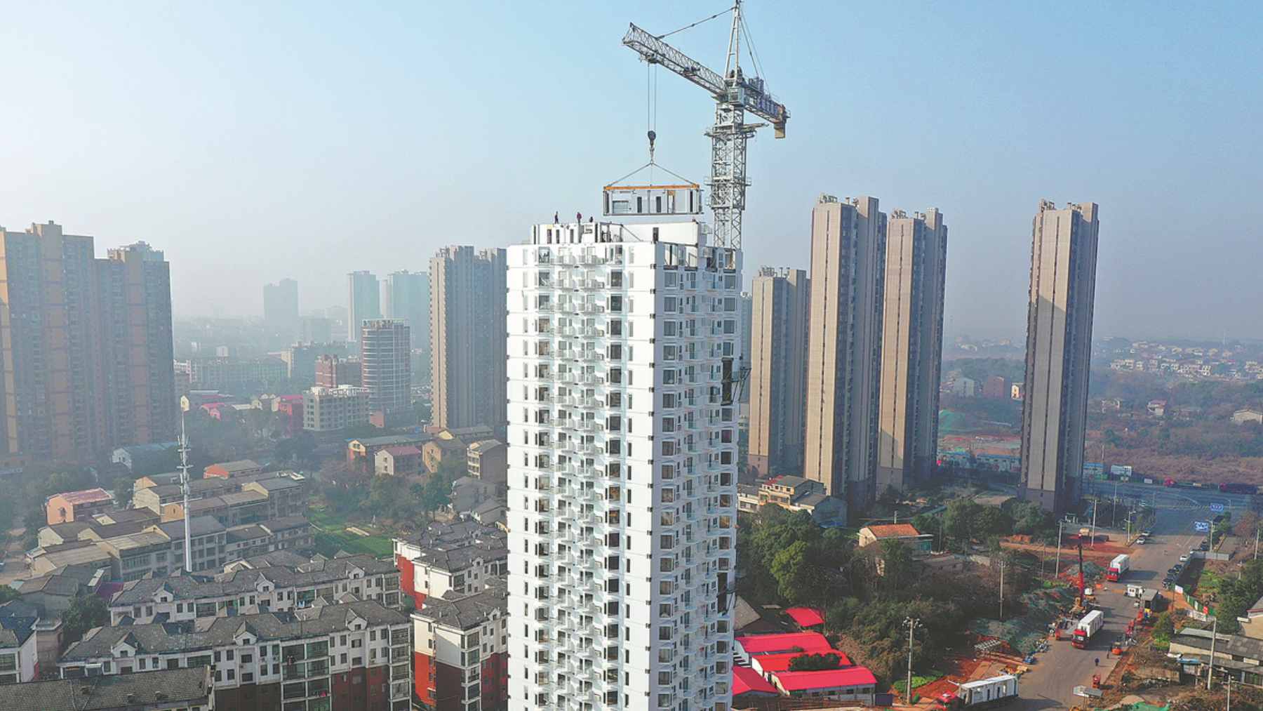 A timelapse view of a 26-story residential tower in China being assembled by stacking pre-fabricated stainless-steel modules via crane.