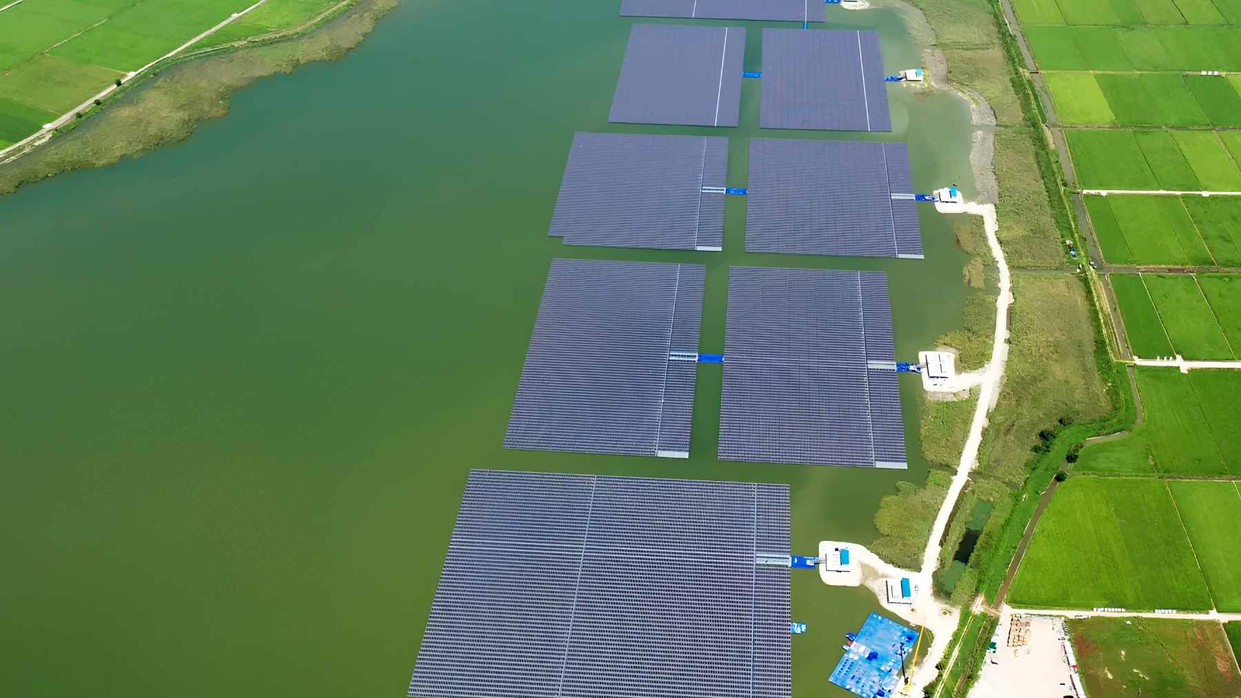 An aerial view of a massive floating solar panel array floating on the blue waters of Kenyir Lake in Malaysia.