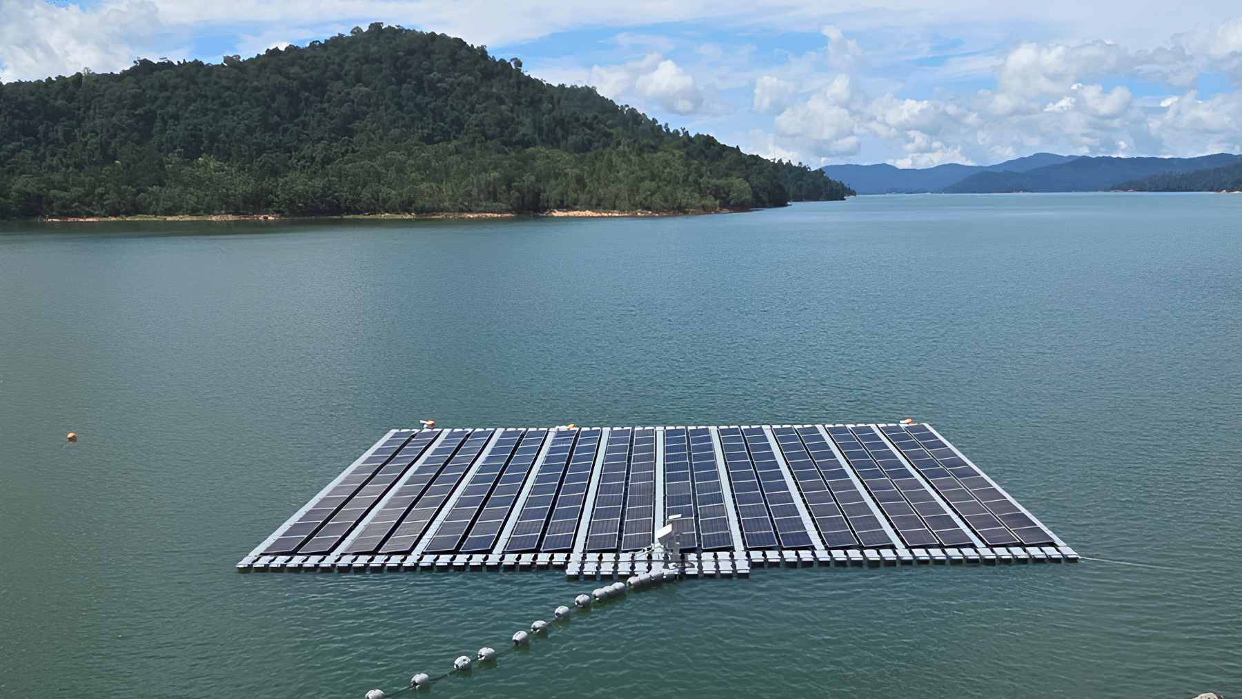 An aerial view of a massive floating solar panel array floating on the blue waters of Kenyir Lake in Malaysia.