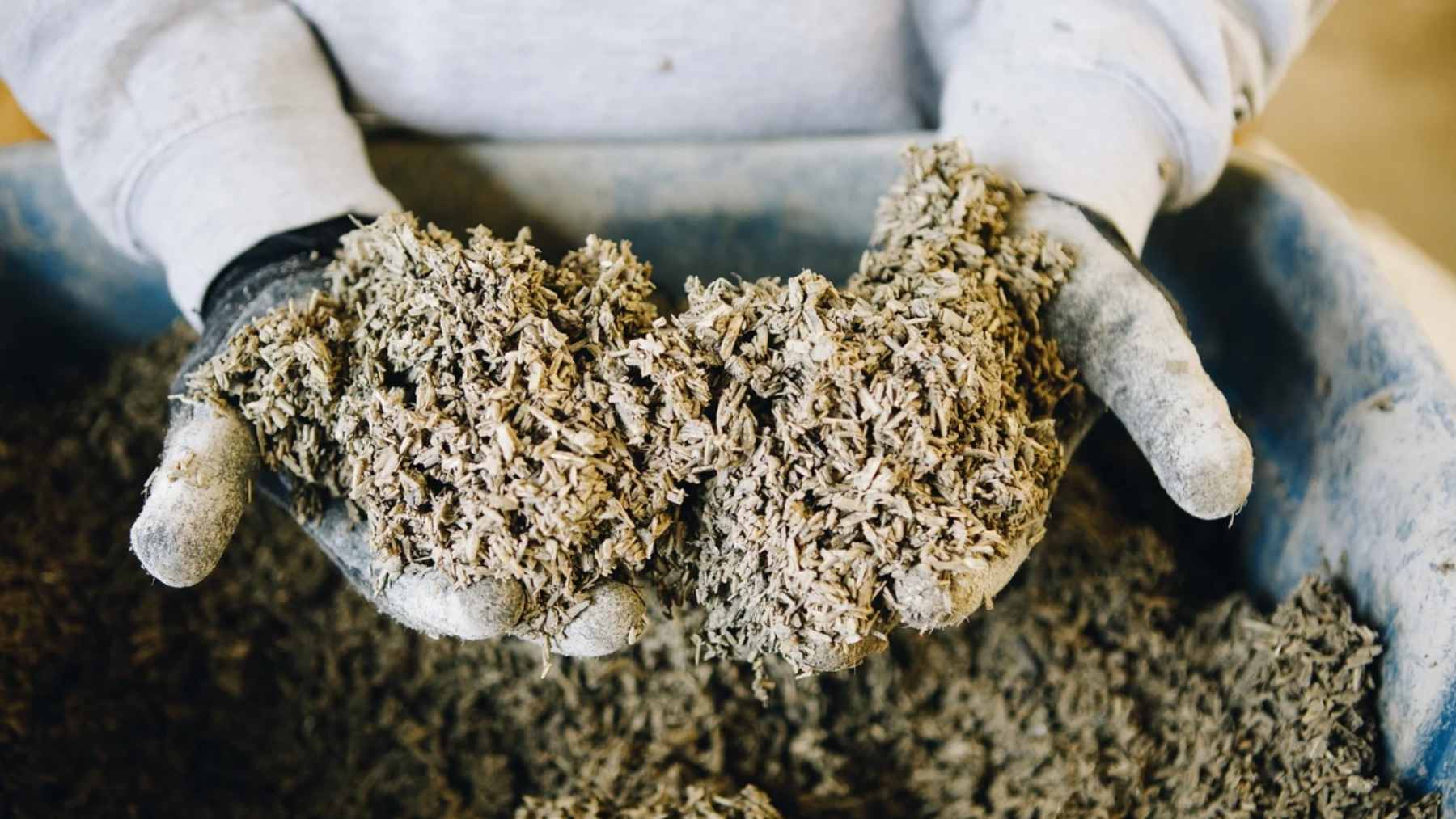 Construction workers applying hempcrete mixture around a wood frame during home building, demonstrating hemp-lime insulation.