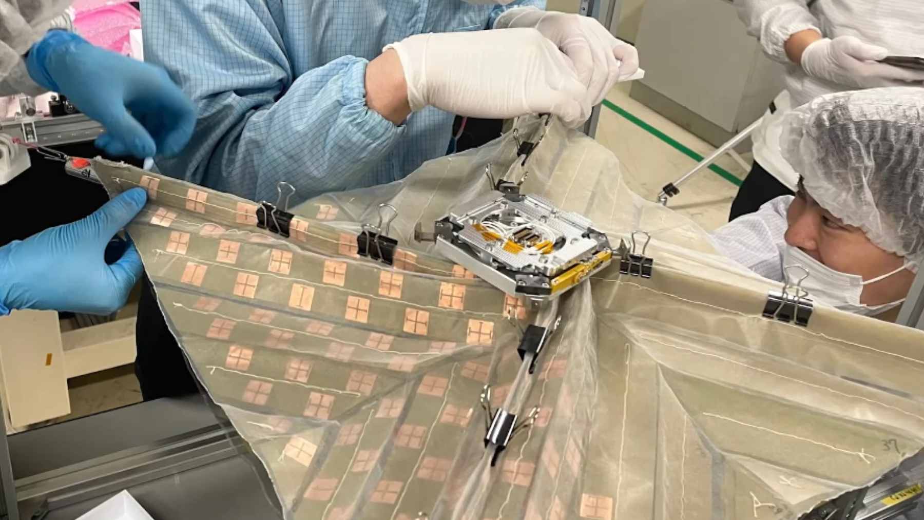 A small, coffee-mug-sized CubeSat deploying its massive, origami-inspired fold-out membrane antenna in low-Earth orbit.