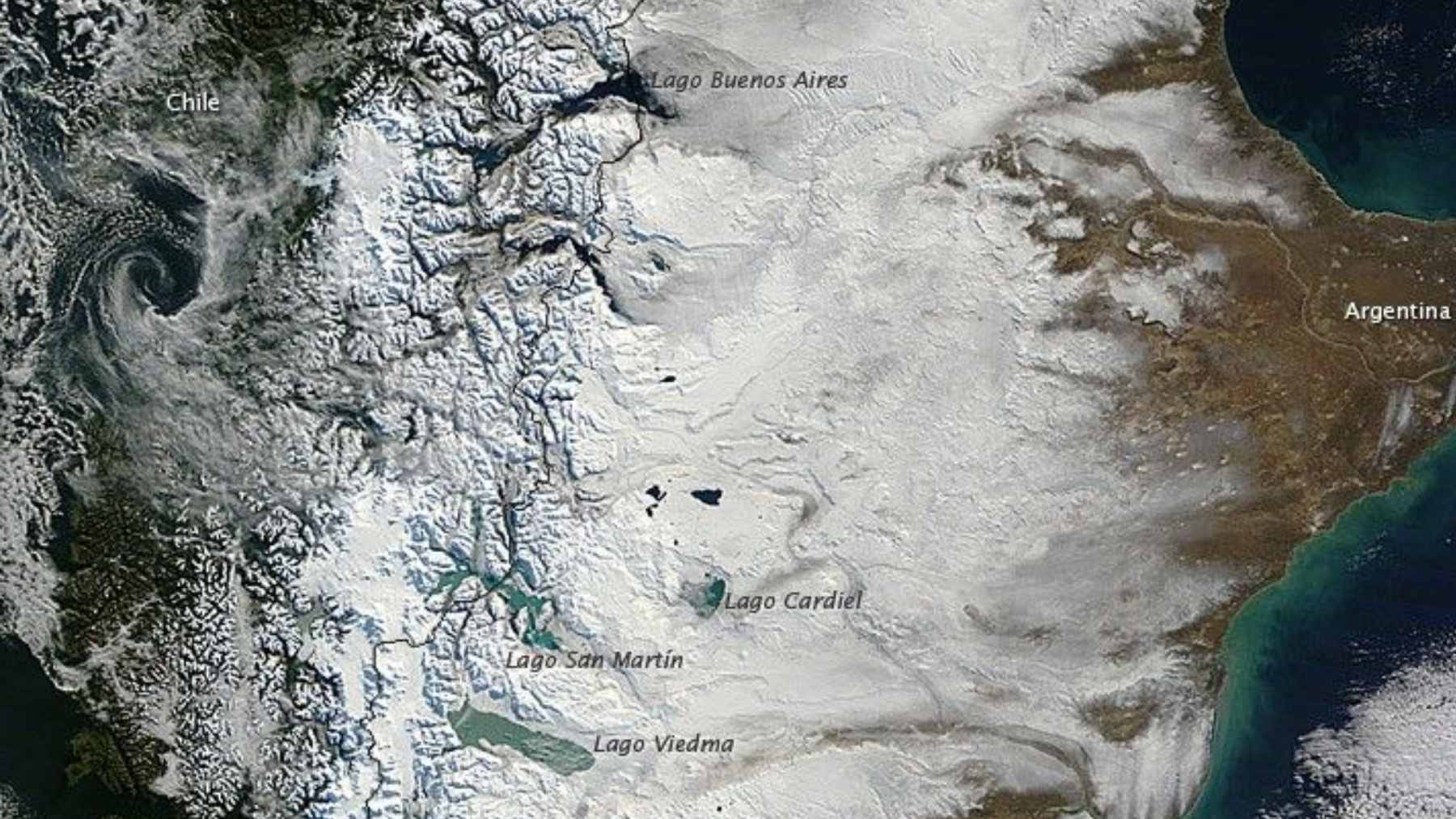 A satellite view from NASA's Landsat 9 showing vibrant red patches across the Andes in Patagonia, mimicking the appearance of red snow.