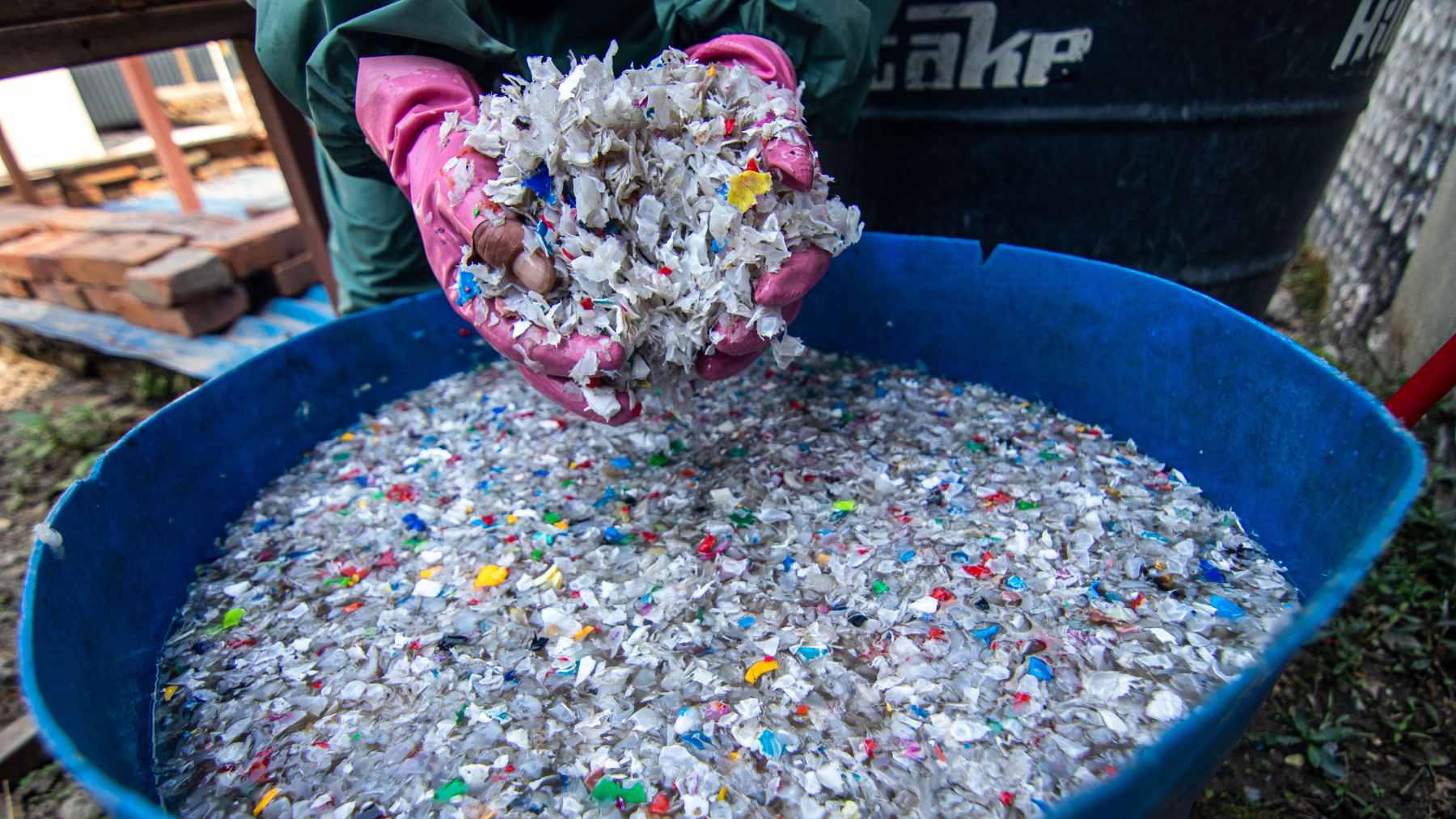 A construction crew in Pokhara, Nepal, mixing shredded plastic waste into hot asphalt for road construction.
