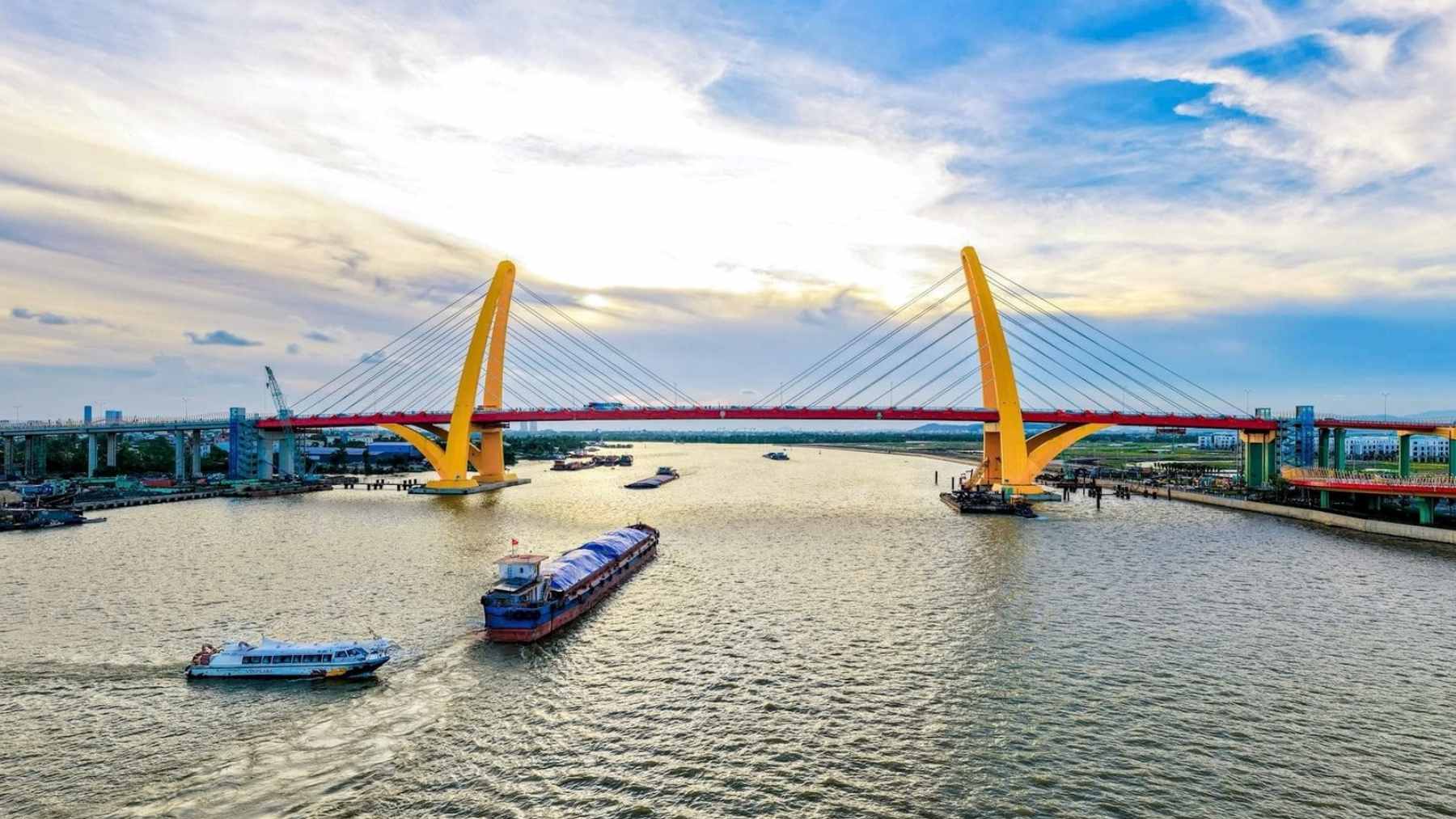 An aerial view of the newly completed Royal Bridge (May Chai Bridge) in Hai Phong, Vietnam, featuring its unique leaning twin-tower design over the Cam River.